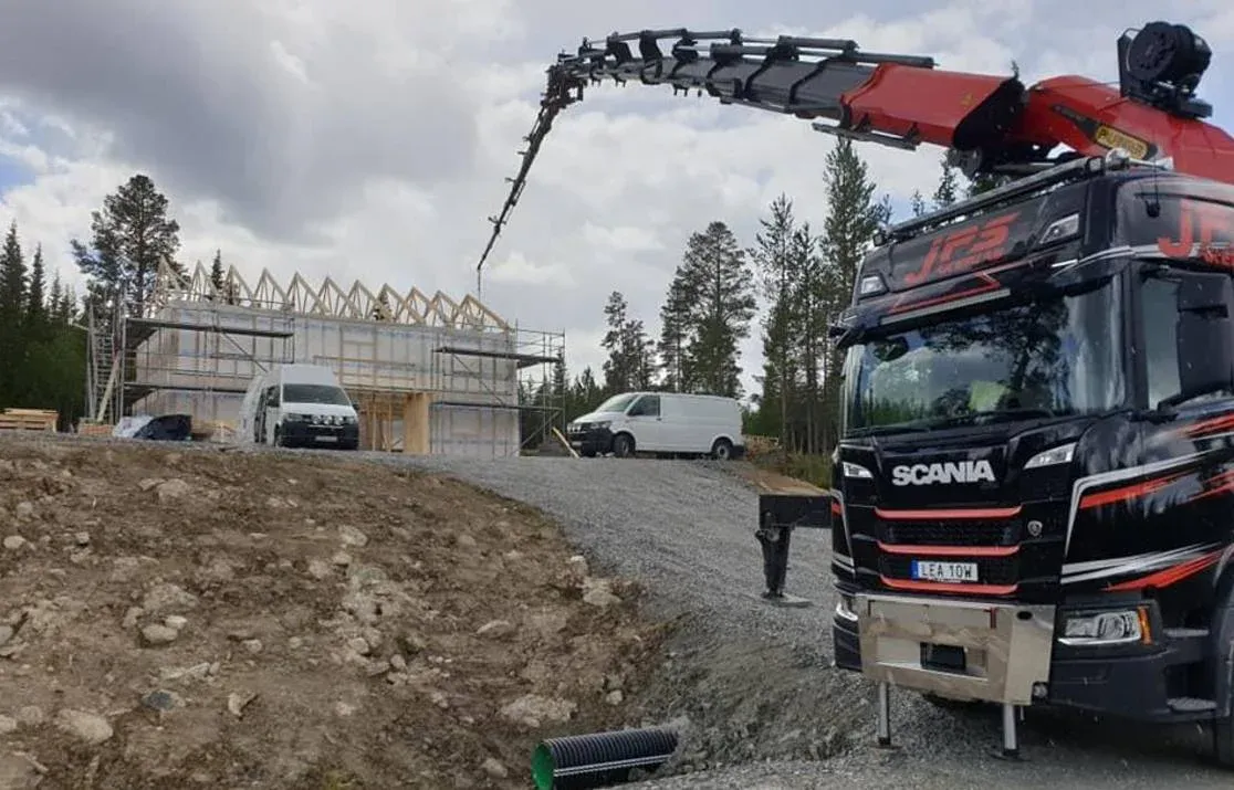 Scania kranbil med utfälld kran på en byggarbetsplats.