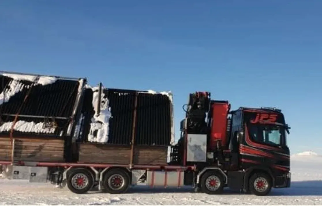 Kranbil lastad med material på snötäckt väg.