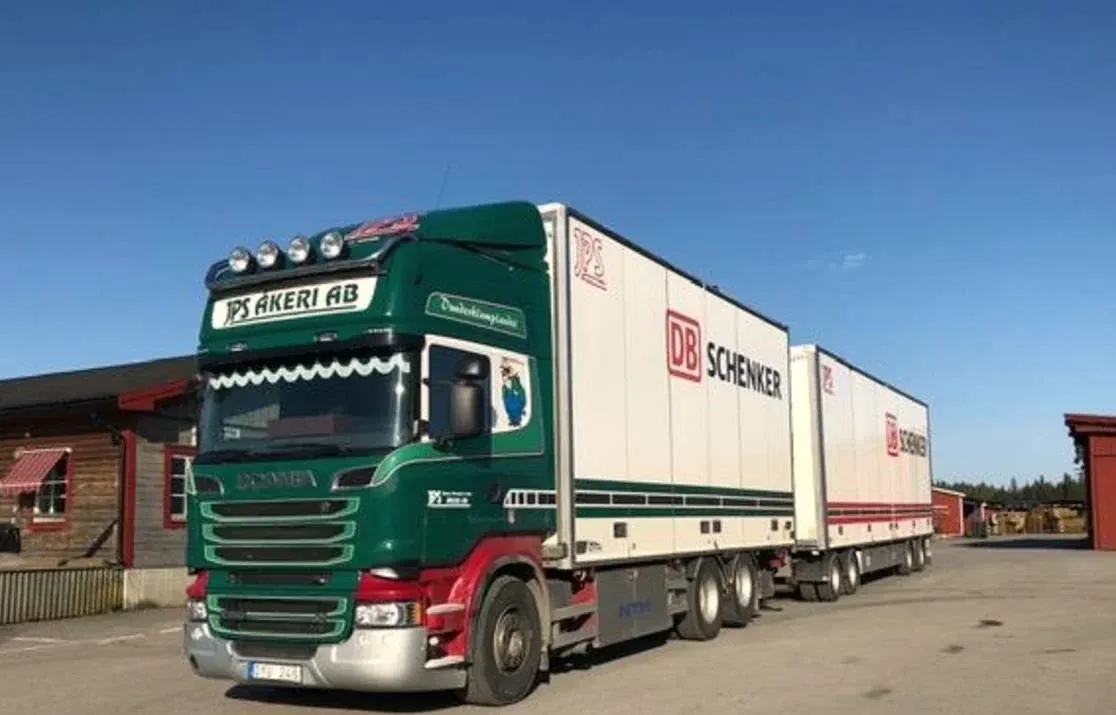 Grön och röd Scania med två DB Schenker-skåp uppställd på terminalplanen.