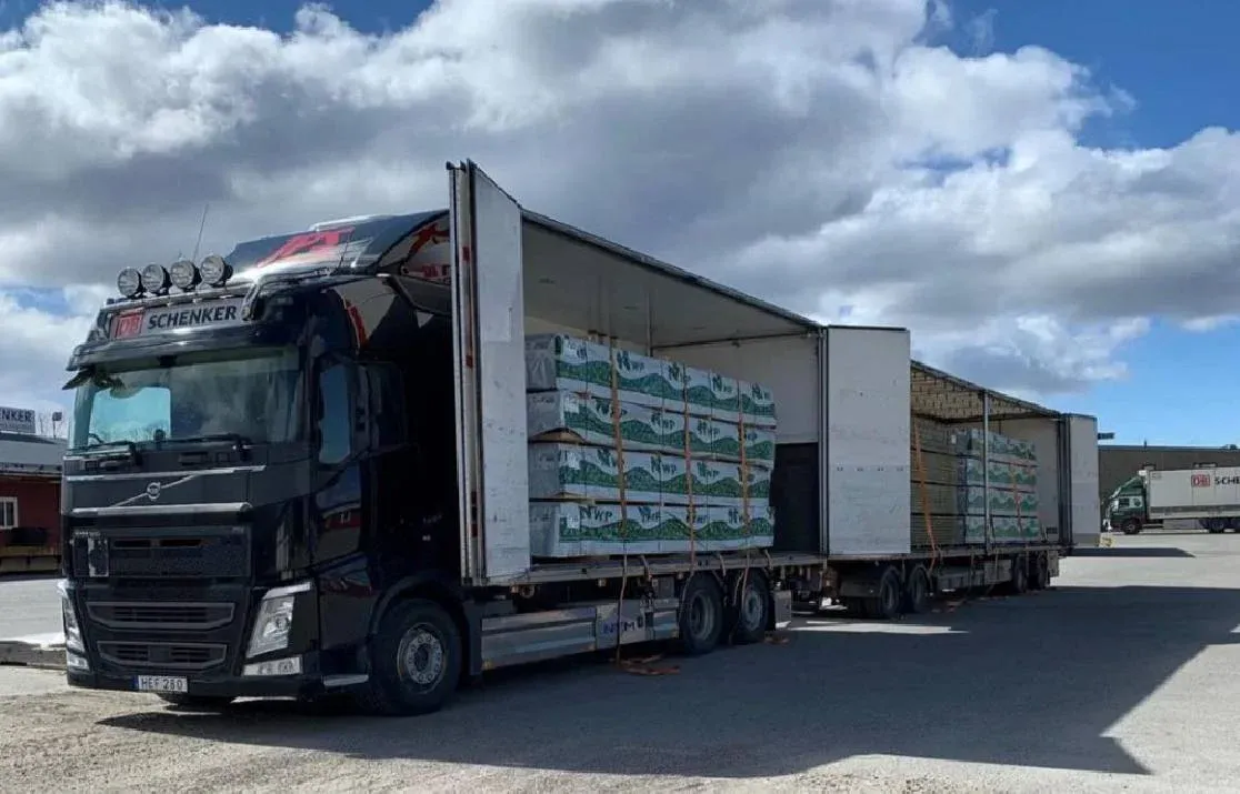 Volvo lastbil med öppet skåp under lastning av pallgods.