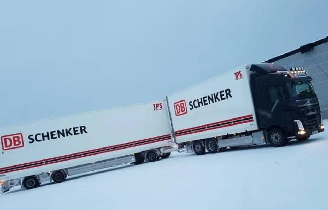 Volvo med DB Schenker-skåp uppställd på snötäckt plan.
